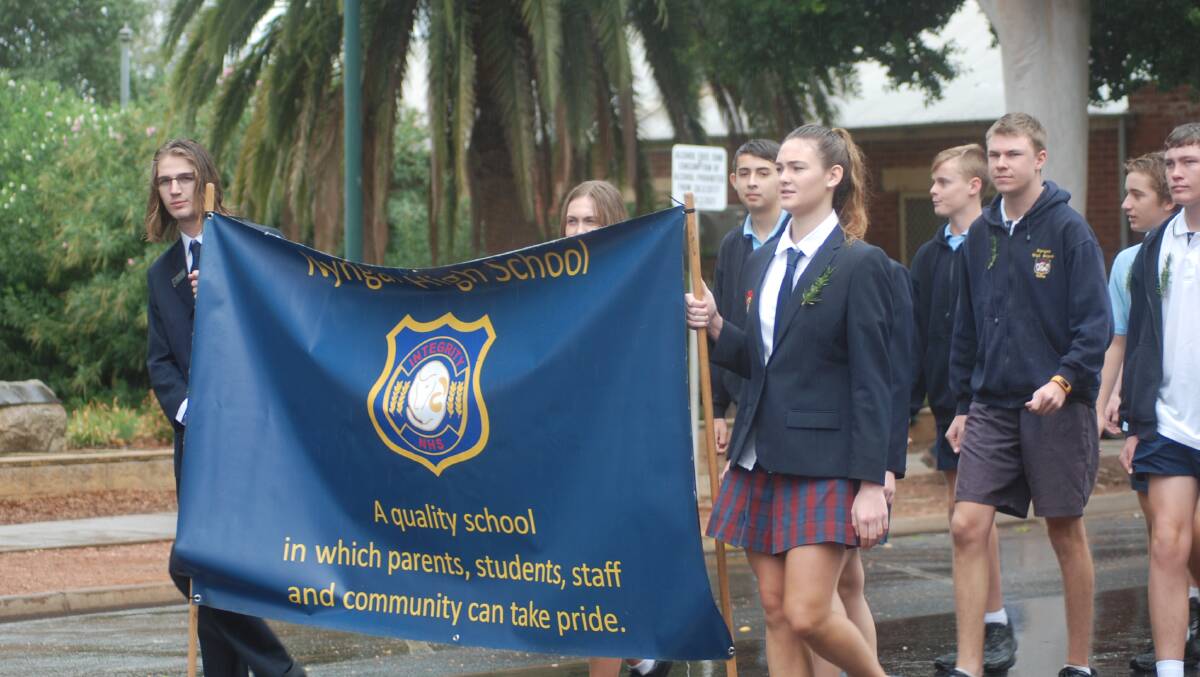 Kasey Douglas walks with the school flag during hte march. 