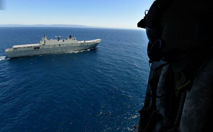 A MRH90 helicopter crew member looks out over the HMAS Canberra during the Royal Australian Navy's joint-enabled, Fleet Training Activity Fleet Concentration Period East 2015 in the East Australian Areas (EAA) in waters off Jervis Bay, the largest exercise conducted in over 4 years involving 12 ships including 2 submarines. The HMAS Canberra a LHD is turning 1 on Saturday 28th November, 2015. Off Jervis Bay, NSW. 26th November, 2015. Photo: Kate Geraghty Photo: Kate Geraghty