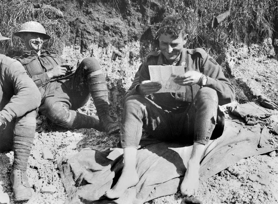 IN TOUCH: 5th Australian Machine Gun company Sergeant Peter O’Connell reads a letter from home at Vendelles on September 17, 1918. Sergeant Arthur James Stewart (l) died of influenza six weeks later. Picture: AWM E03266