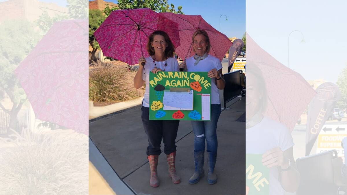 LET IT RAIN: Jodie Stewart and Kate Yabsley had their gumboots and umbrellas out selling tickets in the rain, rain come again competition for the St Joseph's P&F. Photo: ZAARKACHA MARLAN