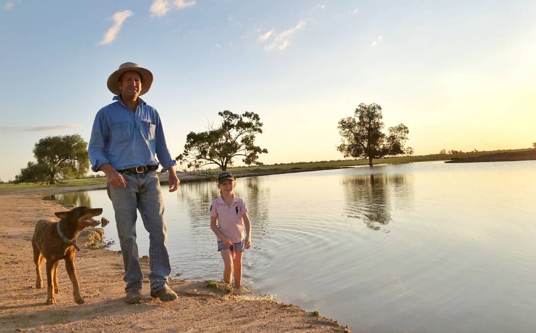 Once a dust storm's playground, Mullengudgery Merino stud manager Scott McMillan and his daughter Raphaella, 9, with their Kelpie Jake are celebrating up to 90mm over the Nyngan property. Photo: Marcia McMillan